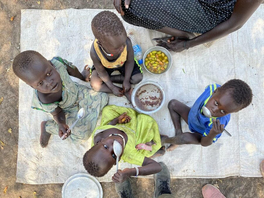 南スーダンの様子 ジョングレイ州アコボ東部の子どもたちが地元の果物を添えたソルガムの昼食を取っています。― 同国で最後に飢きんが宣言されたのは2017年でした。Photo: WFP/Marwa Awad
