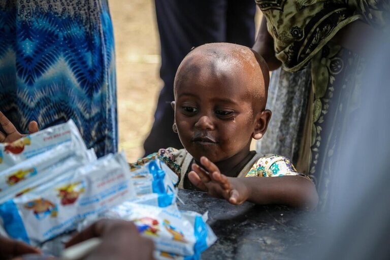 Child picking high-energy biscuits distributed by WFP in response to rising hunger crisis