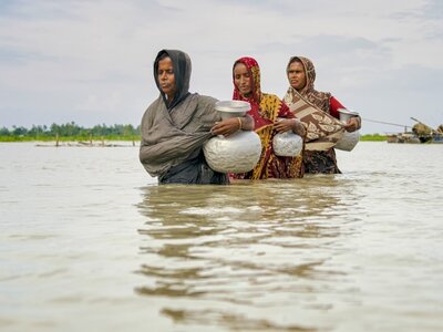 three women walking inside of river