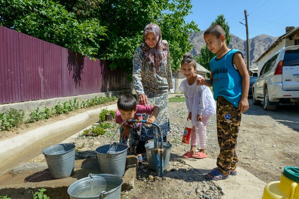 夏の気温が50°Cにも達するキルギスの最も暑い地域に新しく設置された水道管を使う家族。 WFP/Maksim Shubovich