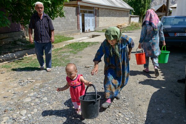 夏の気温が50°Cにも達するキルギスの最も暑い地域に新しく設置された水道管を使う家族。 WFP/Maksim Shubovich