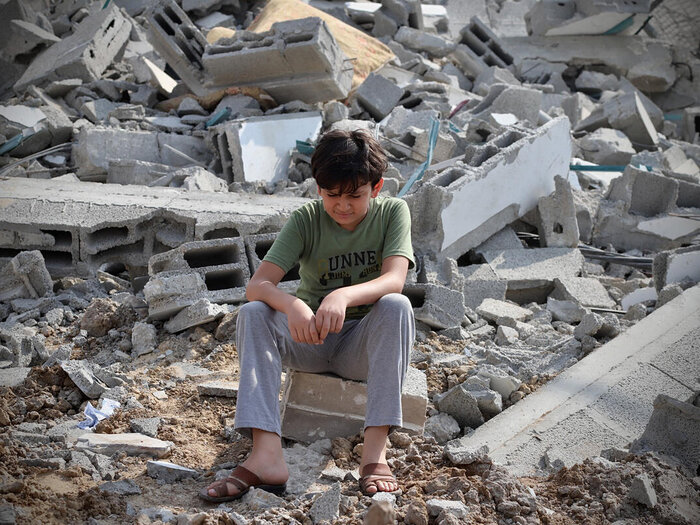 ガザ市内でロケット弾を受けた建物の廃墟に座る少年。