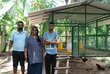 a woman and two men are standing together in front of a cage