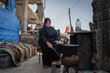 A women sits outside a destroyed building tending to a large covered pot sitting over a fire. Photo: WFP/Maxime Le Lijour