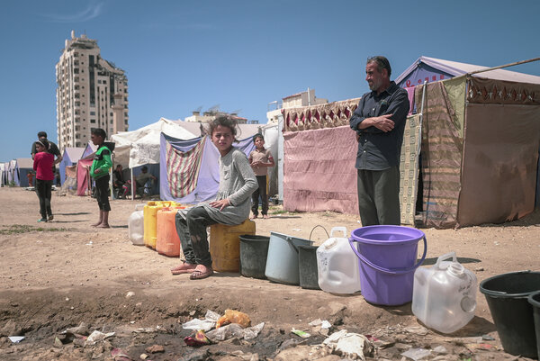 Photo: WFP/Photo library. ガザ市で避難民となったパレスチナ人が列を作り、容器に水を入れるのを待っている。