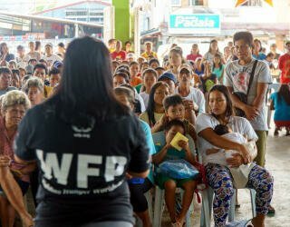 予測型現金支給に参加するイロシン・コミュニティのメンバーに登録方法を説明する国連WFPスタッフ。Photo: WFP Philippines/Arete