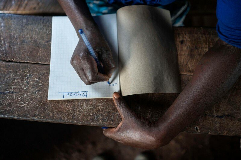 A closeup on a woman writing in a notebook.