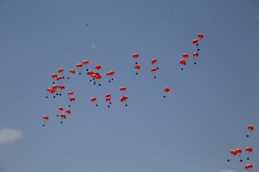 orange parachutes against clear blue sky