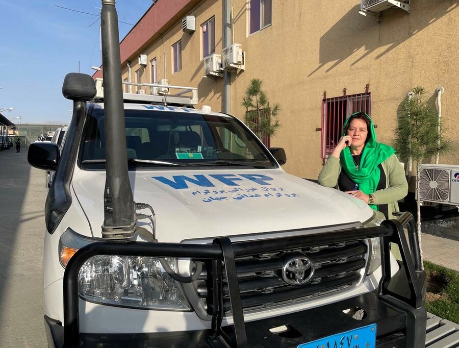 woman in green headscarf leaning on WFP vehicle