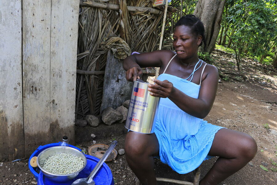 woman in light blue dress cooking peas outside shelter