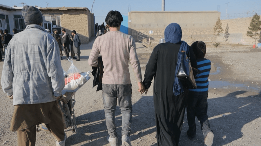 He leaves a food distribution point with this family. Photo: WFP/Jon Dumont