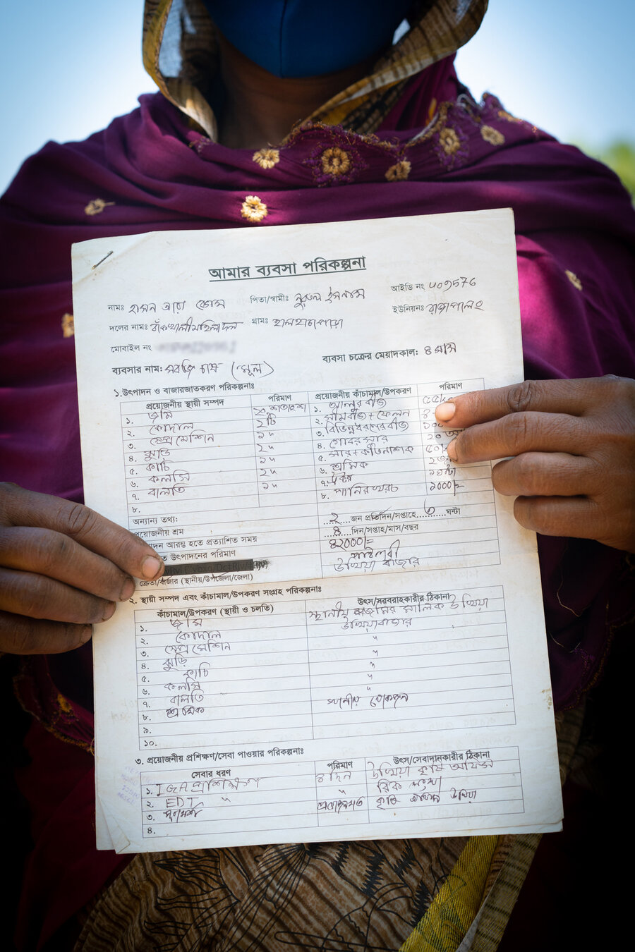 A woman holds a sheet of paper on which she has written her business plan