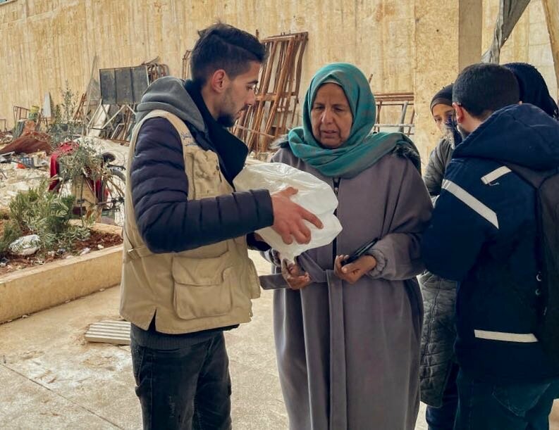 地震後、トルコとの国境近くにあるシリアのイドリブ県で、国連WFPのすぐに食べられる食事を受け取る女性