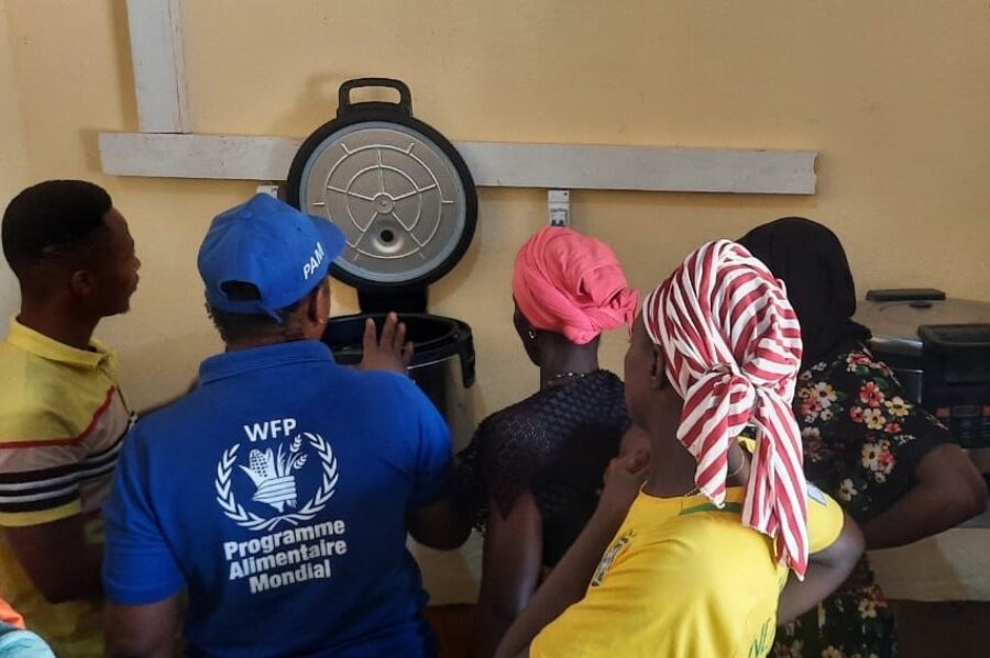 ギニア南部の女性たちに、国連WFPが支援する学校給食を作るためのソーラー調理器の使い方を教えている国連WFPの職員。