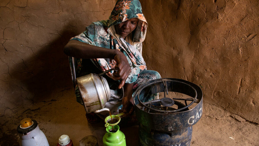 チャドでは、スーダンからの難民、ナディファ・イブラヒムさんが、UNHCRから受け取ったガス調理器を使って自分で淹れたお茶をポットに注ぎます。In Chad, Sudanese refugee Nadifa Ibrahim pours tea she's brewed using a WFP-supplied gas cooker. Photo: WFP/Irshad Khan 