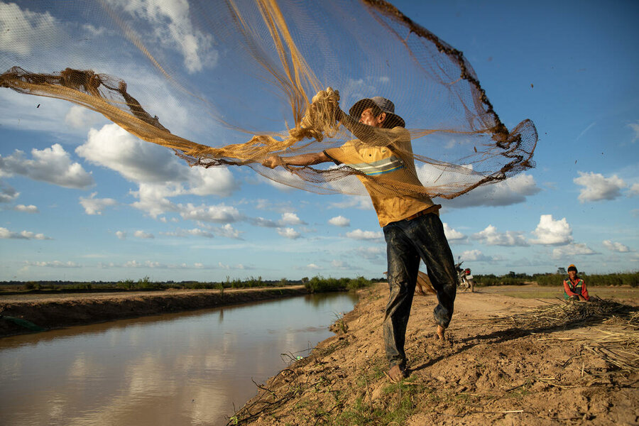 カンボジアのコンポントム県にあるサンブール地区で、国連WFPが支援する運河に漁網を投げ入れる農民のドゥア・ソックさん。
