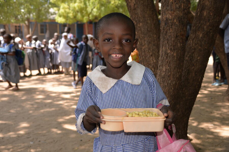 ケニアのカクマ難民キャンプで、国連WFPが提供する温かい学校給食に顔をほころばせるビンジャ・ムナエガベさん。学校給食支援は、生徒たちが通学を続け、より良い人生を選択できるようにするのに役立っています。 Photo: WFP/Rose Ogala