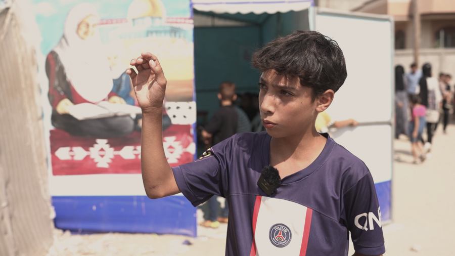 Ahmad in front of a temporary tent school where he studies in central Gaza. Photo: WFP/Jaber Badwan