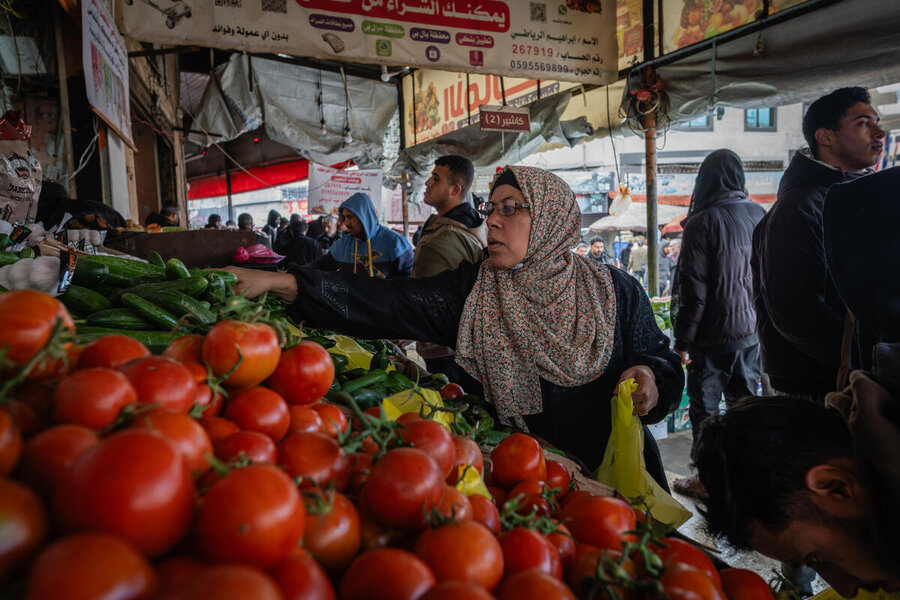 Shoppers select fresh vegetables at a busy market. 