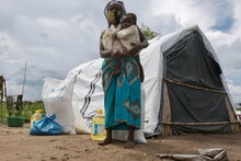 WFP/Grant Lee Neuenburg, Woman and her baby standing in front of a tent in a resettlement camp, Cabo Delgado, Mozambique.